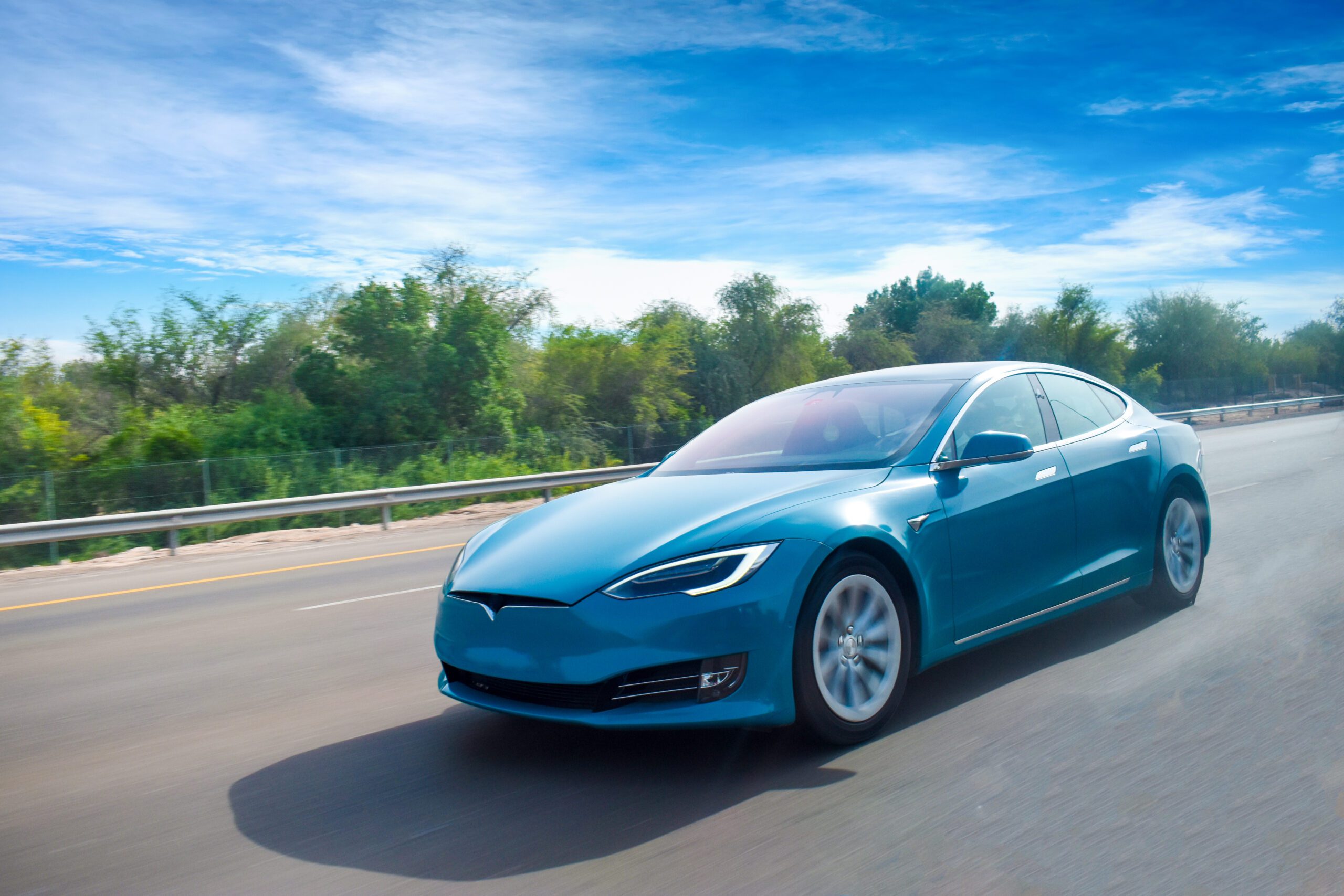 A Blue Coloured Electric Car Cruising on Highway